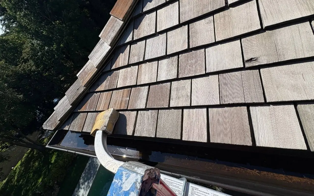 Technician performing Winter Gutter Maintenance in Westchester on a two-story house