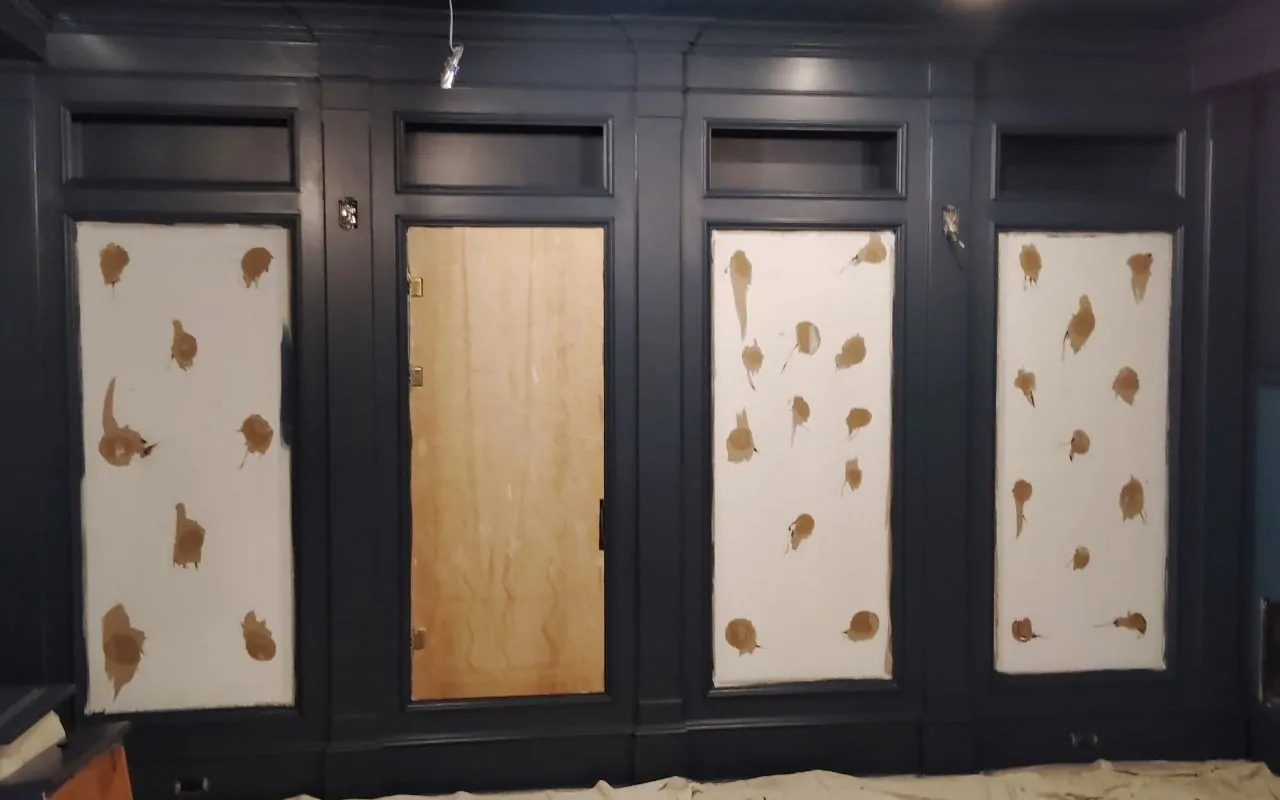 Wall prep after wallpaper inspection showing glue residue and small wall damage before repairs.